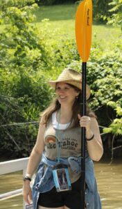 Smiling young woman standing holding paddle